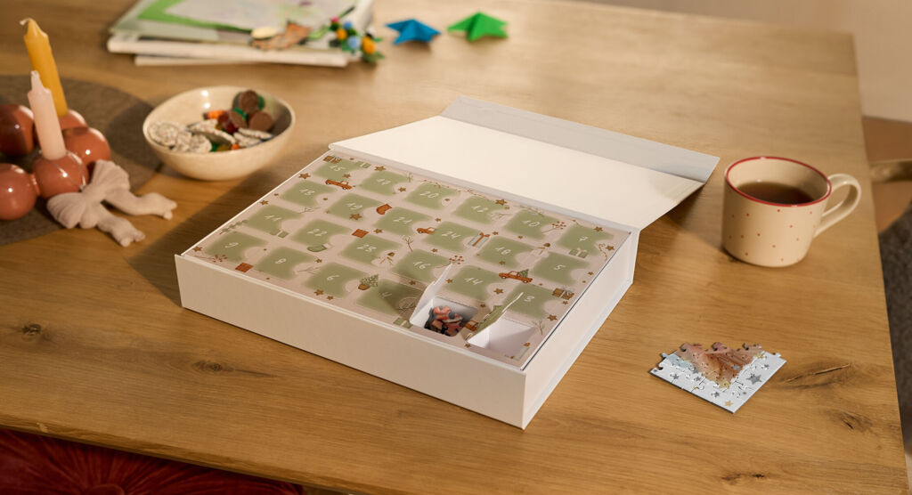 Premium Puzzle-Adventskalender mit zwei geöffneten Türchen und einem bereits gepuzzelten Puzzlestück in weihnachtlicher Umgebung